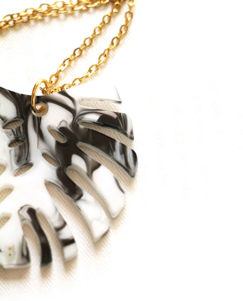 Colar dourado com folha de monstera em preto e branco